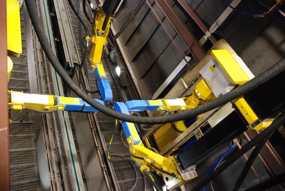 Two wall-mounted robots and two gantry-type robots are in the blastroom blasting freight cars.